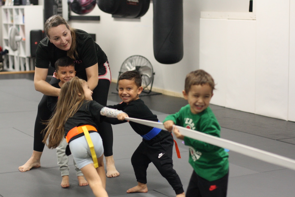 A coach leading little kids through a playful drill